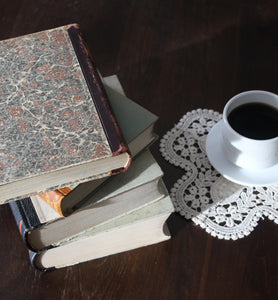 black coffee in white cup beside a stack of books