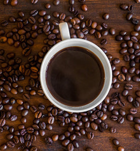 black coffee in white cup surrounded by coffee beans