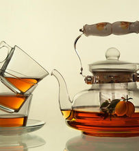 brewed tea in clear glass teapot and three tea cups