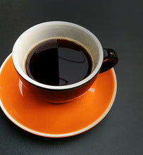 black coffee in an orange and black cup and saucer