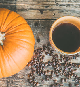 black coffee in ceramic cup beside pumpkin and beans