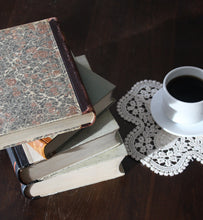 black coffee in white coffee cup beside a stack of books