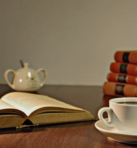 coffee in white coffee cup beside an open book
