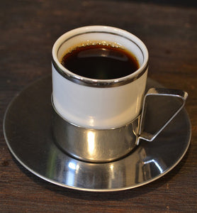 black coffee in stainless steel cup with saucer