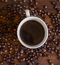 black coffee in white cup surrounded by coffee beans