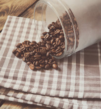 roasted coffee beans spilled from jar onto plaid linen