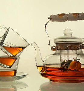 brewed tea in clear glass teapot and three tea cups