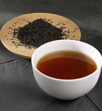 Organic Earl Grey Tea in white teacup beside Earl Grey tea leaves