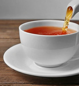 Organic English Breakfast Tea pours from kettle into white teacup