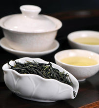 green tea leaves beside two cups of brewed green tea