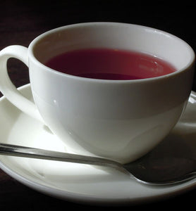 herbal tea in white cup with saucer and spoon