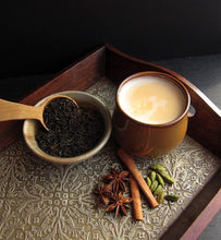 masala chai in ceramic cup beside tea leaves and spices
